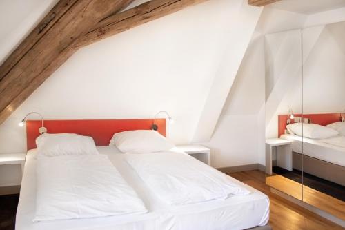 a bedroom with a white bed with a red headboard at KU Hotel by WMM Hotels in Kulmbach