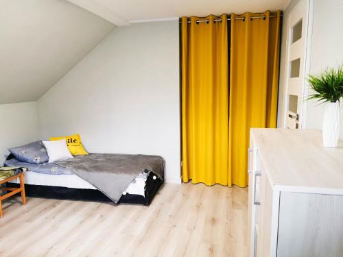 1 dormitorio con cama y cortina amarilla en U Szwagra en Ustka
