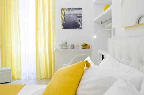 a white bedroom with a yellow pillow on a bed at Maison San Paolo in Sorrento