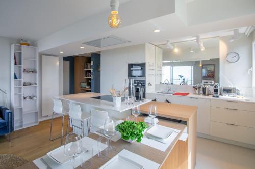 une cuisine avec des placards blancs et une table avec des verres à vin dans l'établissement L'Observatoire, à Pléneuf-Val-André