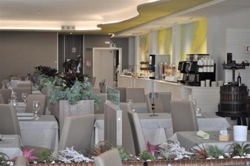 a restaurant with white tables and chairs and a counter at Hotel Marco Polo in Caorle