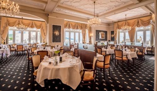 a restaurant with white tables and chairs and chandeliers at The Victoria Hotel & Source Spa in Sidmouth