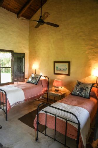 a bedroom with two beds and a ceiling fan at Aguapé Lodge in Colonia Carlos Pellegrini