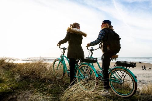 two women standing with bikes on the beach at Bain de forêt - Lodges Cosy & Spa in Neufchâtel-Hardelot