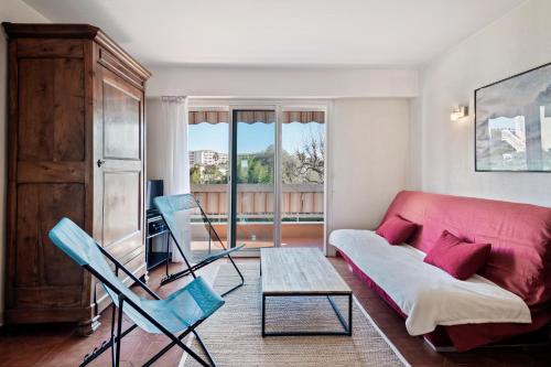 un soggiorno con un divano rosso e 2 sedie blu di Les Jasmins Apartment a Vallauris