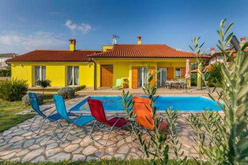 a yellow house with chairs and a swimming pool at Delightful villa with pool for 6 persons in Krmed
