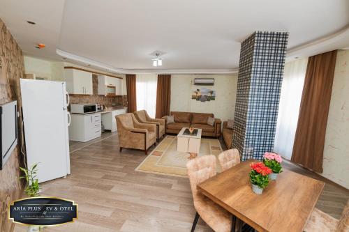 a living room with a table and a kitchen at aria plus ev otel in Çiftlikköy