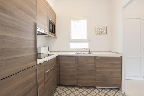 a kitchen with wooden cabinets and a sink at Cala Galdana Apartamentos El Rio in Cala Galdana