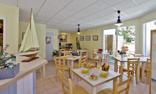 a dining room with tables and a sailboat on the wall at Hôtel de l'Océan in Notre-Dame-de-Monts