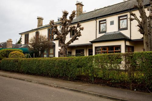 een groot huis met een heg ervoor bij West End Hotel in Nairn