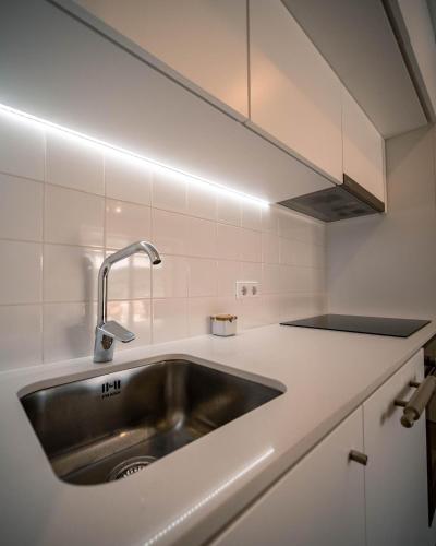 a kitchen with a stainless steel sink and white cabinets at Casa da Várzea - Serra da Estrela in Fornos de Algodres