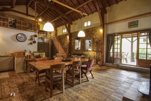 eine Küche und ein Esszimmer mit einem Holztisch und Stühlen in der Unterkunft Les Trois Noyers in Tailhac