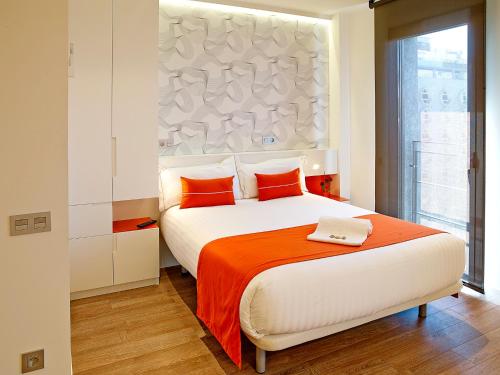 a bedroom with a large bed with an orange blanket at Apart-Suites Hostemplo in Barcelona