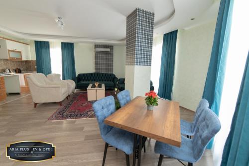 a living room with a wooden table and blue chairs at aria plus ev otel in Çiftlikköy
