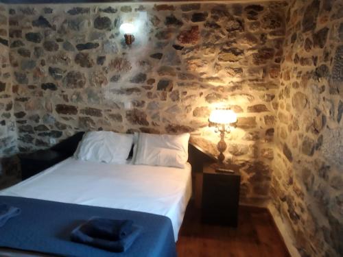 a bedroom with a bed and a stone wall at panos stone tower in Páliros