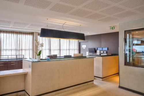an office lobby with a reception desk and a counter at Clarion Paris CDG Airport in Roissy-en-France