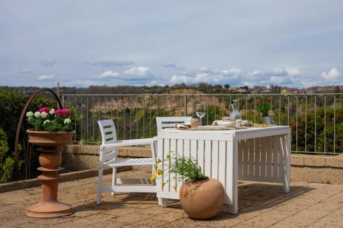 a white table with two chairs and a vase with flowers at Acqua di Civita Beauty & Rooms in Bagnoregio