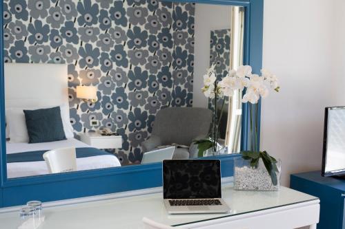 a bedroom with a mirror and a laptop on a desk at Atlantic Palace Hotel in Sorrento
