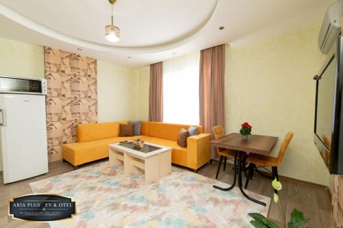 a living room with a yellow couch and a table at aria plus ev-otel in Çiftlikköy