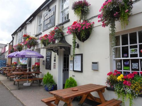 een gebouw met houten tafels en bloemen erop bij The London Inn in Cheltenham