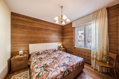 - une chambre avec des murs en bois, un lit et une fenêtre dans l'établissement Casa Rancolin, à Moena