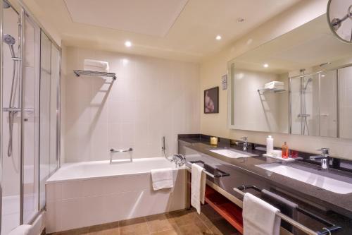 a bathroom with a large tub and two sinks at Clarion Paris CDG Airport in Roissy-en-France