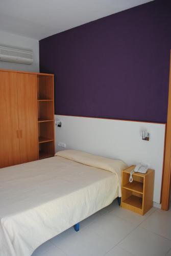 a bedroom with a bed and a purple wall at Hotel Sant Jordi in Segur de Calafell