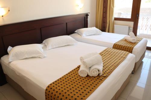 two beds in a hotel room with towels at Hotel Kosta Famissi in Kalabaka