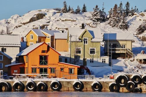 a group of houses on a hill with snow at Heimbrygga Restaurant & Accommodation in Skrova