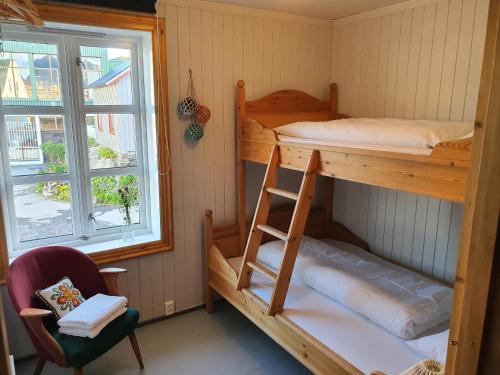 SkrovaにあるHeimbrygga Restaurant & Accommodationの二段ベッド2台、椅子、窓が備わる客室です。