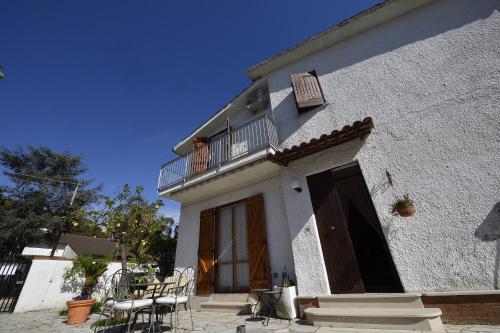 a white house with a balcony and tables and chairs at Villa Dafne con ampio giardino, pochi minuti dal mare Fondi Sperlonga in Fondi