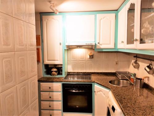 uma cozinha com armários brancos e um lavatório em My Sweet Ribeira 2 no Porto