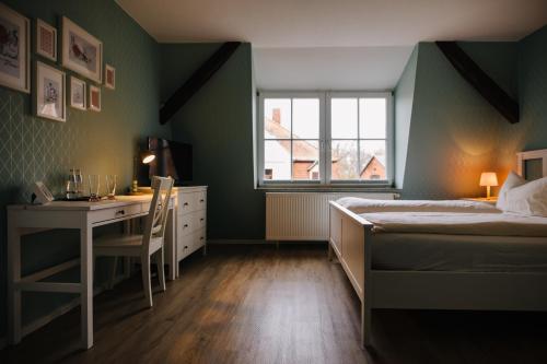 a bedroom with a bed and a desk and a window at SCHULZENS Brauerei & Hotel in Tangermünde