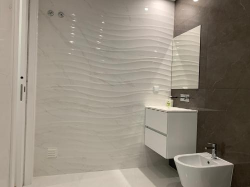 a bathroom with a toilet and a sink and a shower at Apartamentos Quebra-Mar 2 in Nazaré
