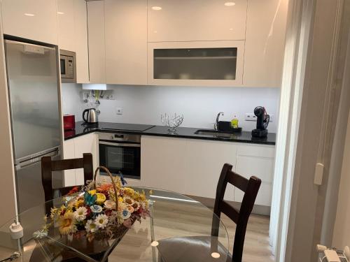 a kitchen with a glass table with flowers on it at Apartamentos Quebra-Mar 2 in Nazaré