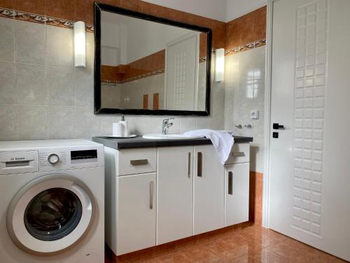 a bathroom with a washing machine and a sink at PORTA HOME modern and hospitable in Naxos Chora