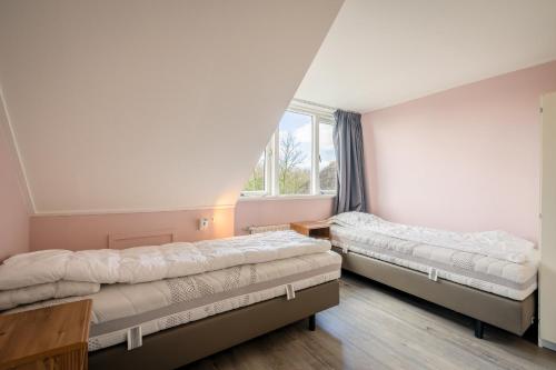 two beds in a room with a window at Nieuwlanderweg 55 in De Waal