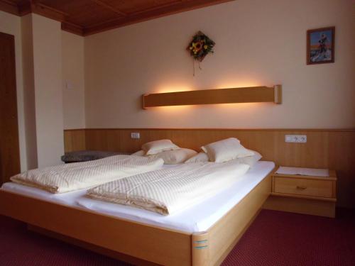 a bedroom with a bed with white sheets and pillows at Ferienwohnungen Rahm in Mayrhofen