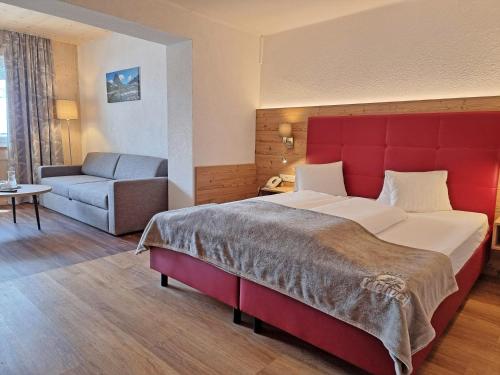 Pokój hotelowy z dużym łóżkiem i kanapą w obiekcie Hotel Gasthof Edelweiß w mieście Sankt Jakob in Defereggen