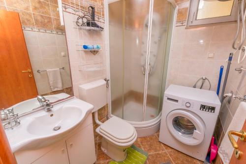 een badkamer met een wastafel en een wasmachine bij Apartment Mario in Rogoznica