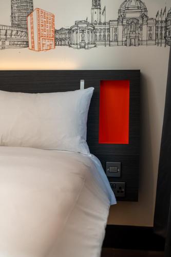 a bedroom with a bed with a red picture on the wall at easyHotel Cardiff in Cardiff