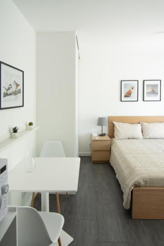 une chambre blanche avec un lit et un bureau dans l'établissement Studio indépendant chez l’habitant au calme (n°2), à Dompierre-sur-Yon