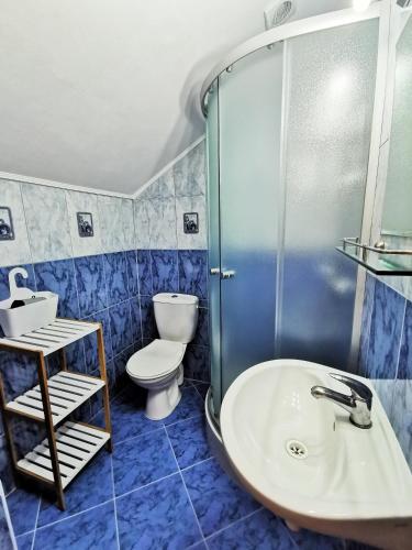a blue tiled bathroom with a sink and a toilet at Romir Pokoje Bardzo Gościnne in Sztutowo
