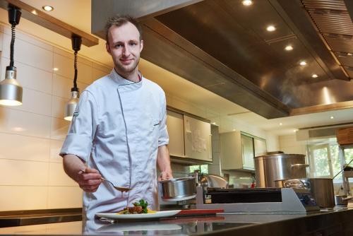 a man standing in a kitchen with a plate of food at Hotel 't Kruisselt in De Lutte