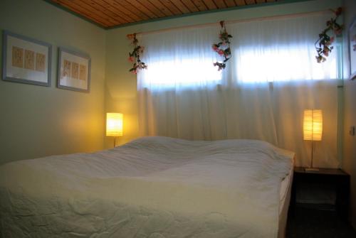 a bedroom with a white bed with a window and two lamps at Hardanger Feriesenter Nesvika in Norheimsund
