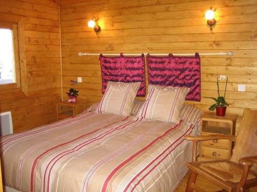 a bedroom with a bed in a log cabin at La Closerie des Arts in Gabillou