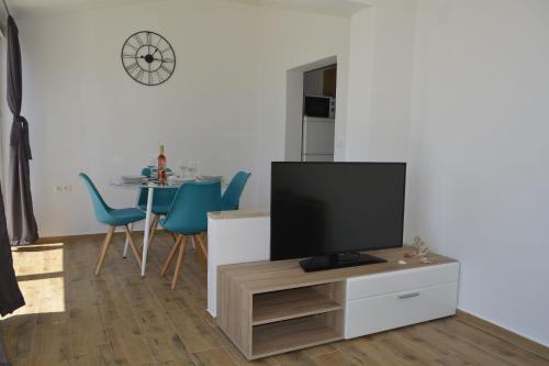 ein Wohnzimmer mit einem TV und einem Tisch mit blauen Stühlen in der Unterkunft Apartments Marija in Ivan Dolac
