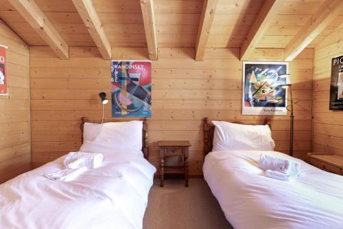 two beds in a room with wooden walls at Chalet Mouettes in Riddes
