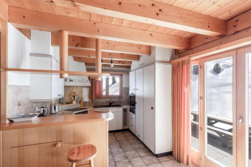 a kitchen with white cabinets and a wooden ceiling at Chalet Mouettes in Riddes