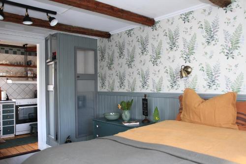 um quarto com uma cama e uma parede com temática florestal em B&B Bland ormbunkar och rosor em Falkenberg